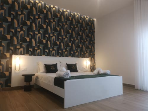 Modern double bedroom at Ruah Pompei with geometric patterned headwall, white bed, twin sconces, and air conditioning in