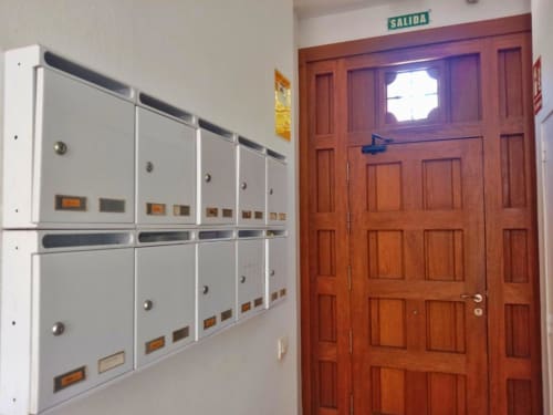 Buzones de apartamento y puerta de salida de madera con letrero 'Salida' en Top Home Integra, Jerez de la Frontera