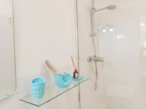 Ducha moderna del apartamento Top Home Integra en Jerez con accesorios azules en repisa de cristal
