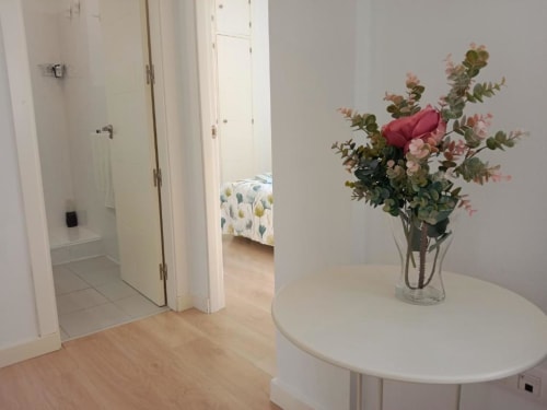 Moderno pasillo de apartamento en Top Home Integra, Jerez de la Frontera, con puertas blancas, suelos de madera y flores frescas