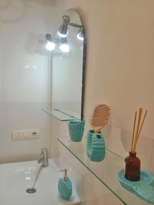Baño moderno con tocador, espejo iluminado, accesorios turquesas y portacepillos de madera en apartamento Top Home Integra
