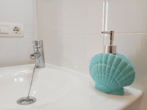 Lavabo del apartamento Top Home Integra en Jerez de la Frontera con dispensador de jabón turquesa en forma de concha y accesorios cromados