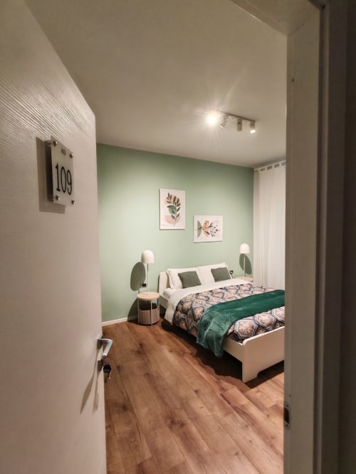 Camera 109 dell'AD Trastevere Guest House a Roma con letto dai dettagli verdi, arte botanica alle pareti e pavimento in legno.