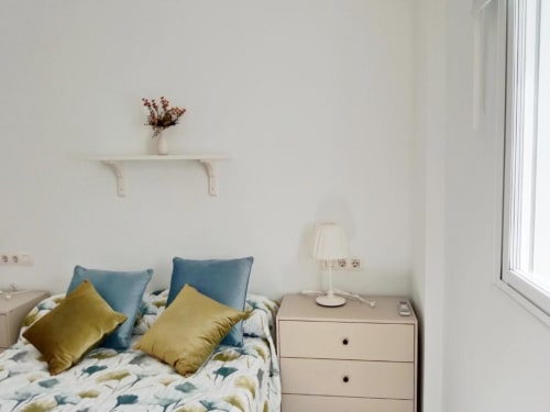 Dormitorio moderno en Jerez de la Frontera con cojines coloridos, ropa de cama estampada y decoración minimalista
