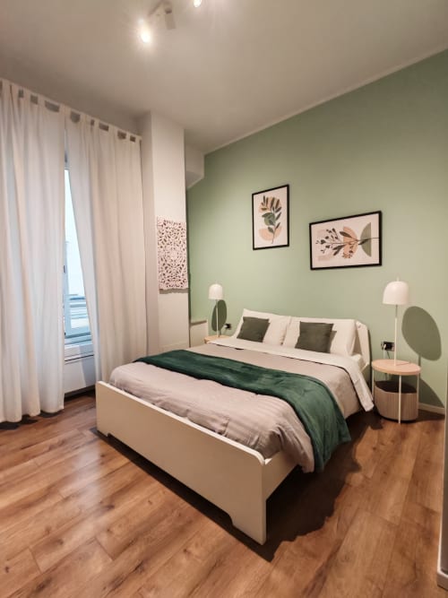 Camera moderna presso AD Trastevere Guest House Roma con parete accent verde salvia, letto bianco, biancheria verde scuro, pavimentazione in legno