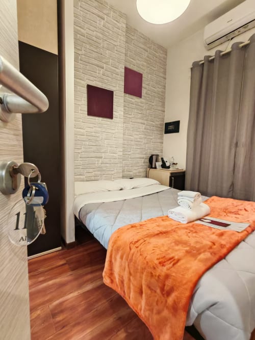 Camera moderna presso AD Trastevere con muri in mattoni, accenti arancioni e letto confortevole a Roma