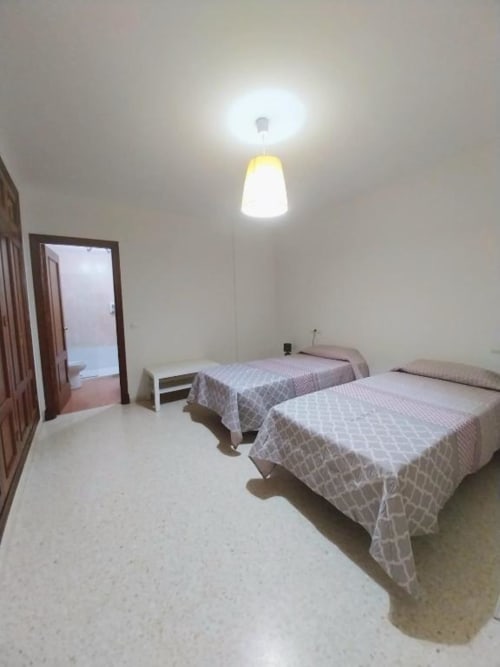Dos camas gemelas en luminoso dormitorio del Top Home Integra, Jerez de la Frontera con vistas al jardín