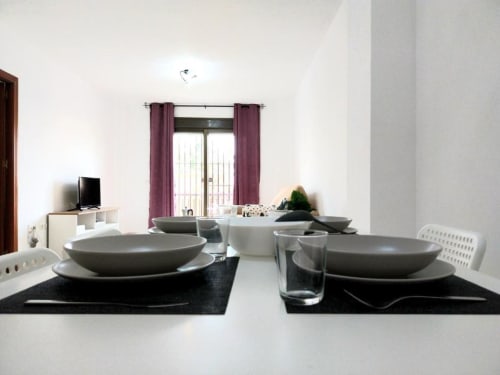 Comedor moderno en apartamento Top Home Integra de Jerez de la Frontera con elegante montaje de mesa y vistas al jardín