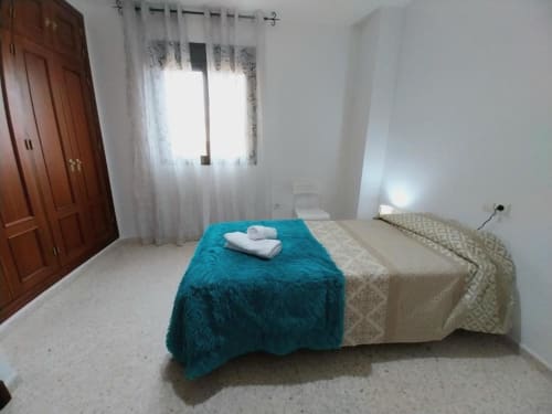Dormitorio luminoso en apartamento Top Home Integra de Jerez de la Frontera con ropa de cama turquesa y vistas al jardín