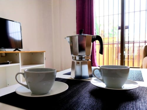 Dos tazas de café en platos con cafetera moka en apartamento con vistas al jardín en Top Home Integra, Jerez de la Frontera