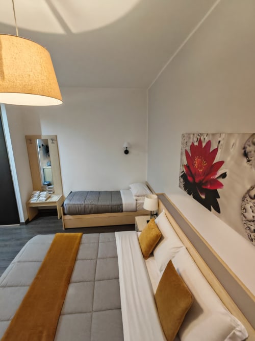 Camera moderna dell'AD Trastevere Guest House a Roma con due letti, mobili in legno, quadro con fiori rossi e lampade a sospensione