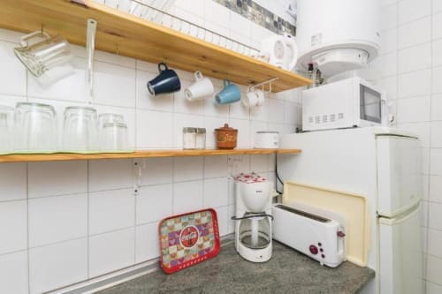 Rincón de cocina en apartamento Top Home Integra de Jerez de la Frontera con estantes de madera, electrodomésticos blancos y decoración vintage