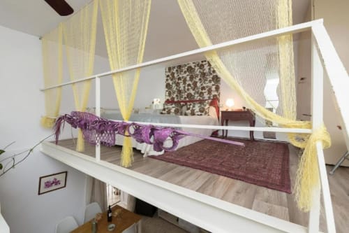 Cama con dosel, cortinas amarillas y detalles en púrpura en el apartamento Top Home Integra de Jerez de la Frontera
