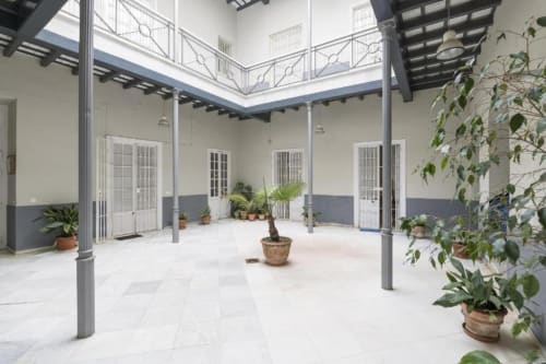 Patio luminoso en Top Home Integra de Jerez de la Frontera con pisos de azulejos blancos, plantas en macetas y barandillas de nivel superior