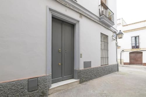 Puertas dobles grises y entrada arqueada en patio de muros blancos del apartamento Top Home Integra, Jerez de la Frontera