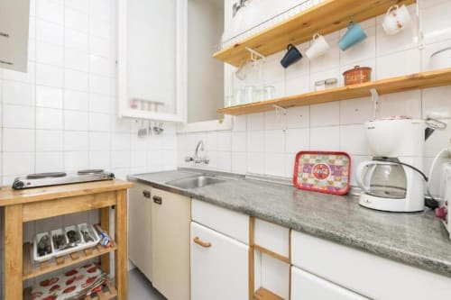 Cocina moderna con estanterías de madera, muebles blancos y encimeras grises en un apartamento de Jerez de la Frontera