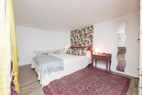 Dormitorio espacioso en Top Home Integra, Jerez de la Frontera, con cama matrimonial, acentos burdeos y espejo curvo moderno
