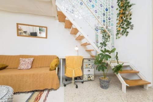 Interior moderno del apartamento en Top Home Integra, Jerez de la Frontera con sofá amarillo, escaleras de madera y plantas decorativas