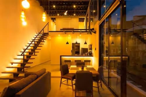 Modern loft interior at Anita Ocean View, Puerto Vallarta with yellow-lit dining area, bar seating, staircase, and ocean view