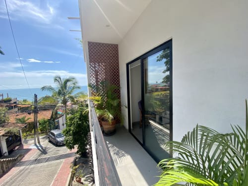 Modern loft balcony at Anita Ocean View, Puerto Vallarta with sea views, palm plants, and black-framed doors