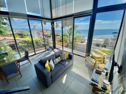 Modern loft at Anita Ocean View, Puerto Vallarta with ocean views, blue sofa, and floor-to-ceiling windows overlooking the