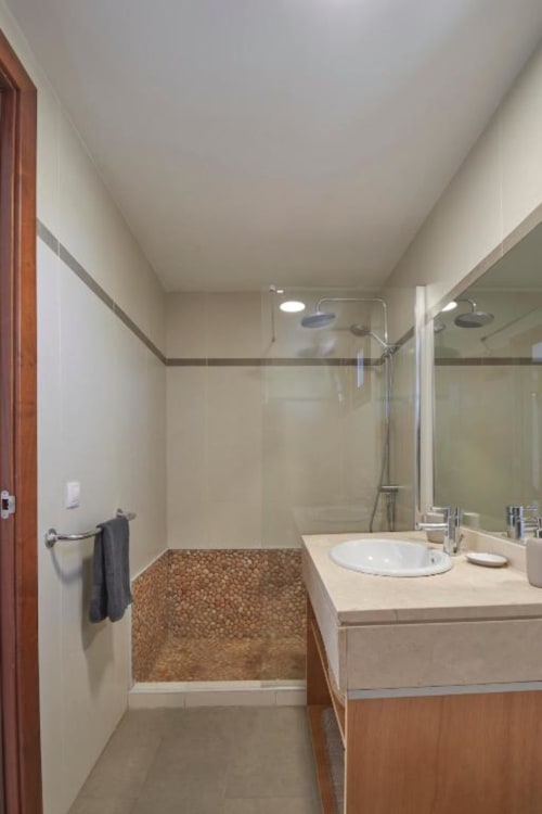 Baño moderno en Villa Cavendish con ducha de efecto lluvia, lavamanos y detalles en piedra en Playa Blanca