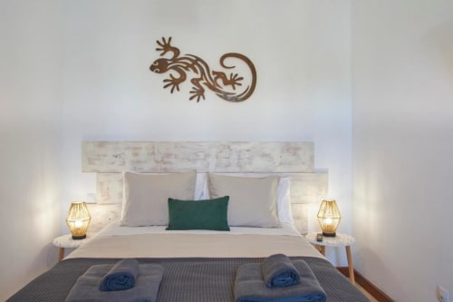 Dormitorio moderno en Villa Cavendish con arte decorativo de lagartija en la pared, iluminación cálida y cojín de acento verde