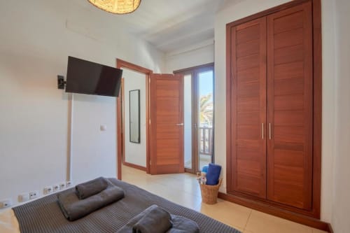 Espacioso dormitorio de apartamento en Villa Cavendish, Playa Blanca con puertas de madera, TV, vistas al balcón y mobiliario moderno