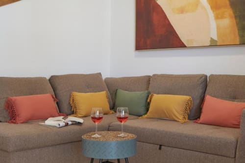 Sala de estar del apartamento Villa Cavendish con sofá seccional beige, cojines coloridos, copas de vino y obra de arte abstracta