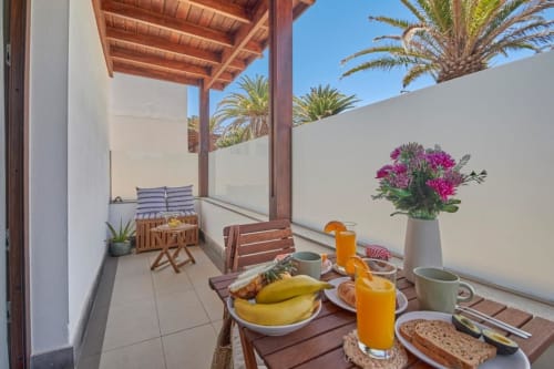 Terraza para desayunar en Villa Cavendish, Playa Blanca, con frutas frescas, jugos y vistas al océano enmarcadas por palmeras