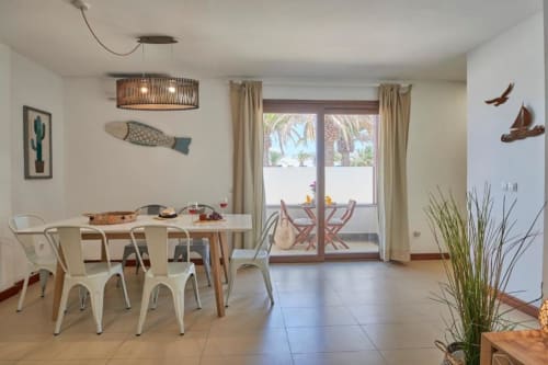 Comedor del apartamento Villa Cavendish en Playa Blanca con vistas al jardín, sillas blancas y decoración costera