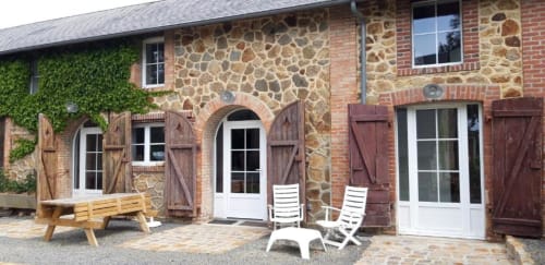 La Longère stone cottage at Le Petit Lustucru B&B in Avranches, France, with brick facade, wooden shutters, terrace seating,