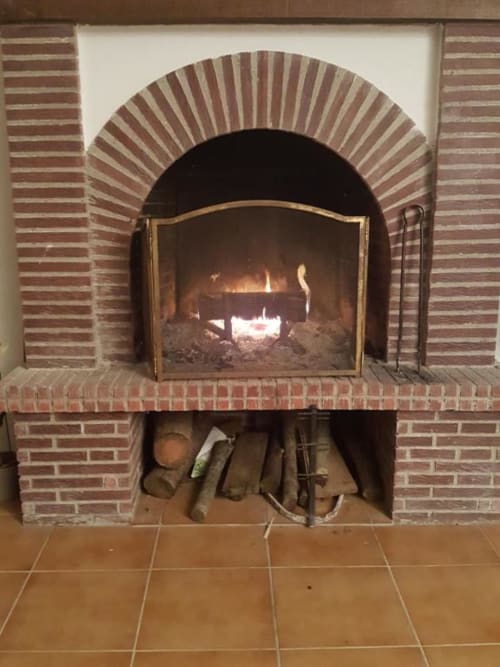 Brick fireplace with arched opening and burning fire at Le Petit Lustucru B&B in Avranches, France