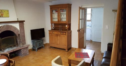 Rustic living room in Le Petit Logis at Avranches B&B, featuring fireplace, wooden furniture, and garden view access