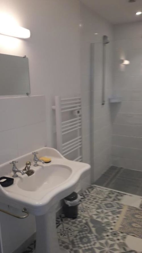 Modern bathroom with white sink, shower area, and heated towel rail at Le Petit Lustucru B&B in Avranches