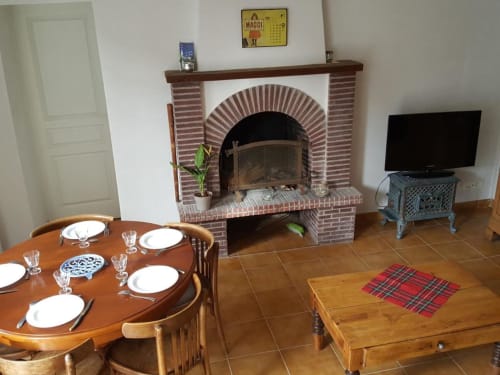 Le Petit Lustucru dining room in Avranches with brick fireplace, set table, and TV