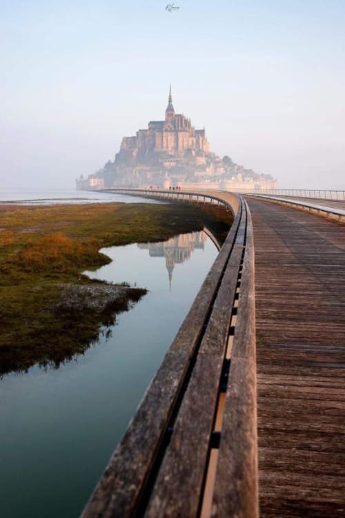 Mont-Saint-Michel castle reflected in water with wooden boardwalk, Avranches, France