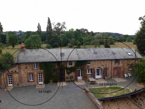 Aerial view of Le Petit Lustucru B&B in Avranches, France, showing two stone cottages with slate roofs and manicured gardens