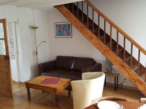 Modern living room at Le Petit Logis in Avranches with brown leather sofa, cream armchair, wooden coffee table, and wooden