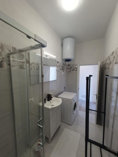 Bagno moderno a Siracusa Sun&Home con doccia, lavandino, lavatrice e pavimenti in piastrelle bianche