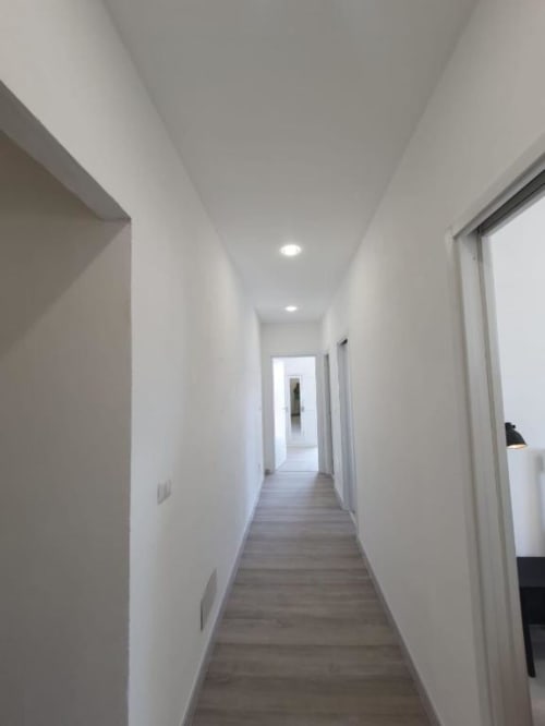 Corridoio moderno nell'appartamento Siracusa Sun&Home con pareti bianche, pavimentazione in legno e illuminazione incassata