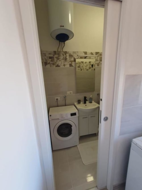Bagno e lavanderia compatti con lavatrice, lavabo e specchio nell'appartamento Siracusa Sun&Home