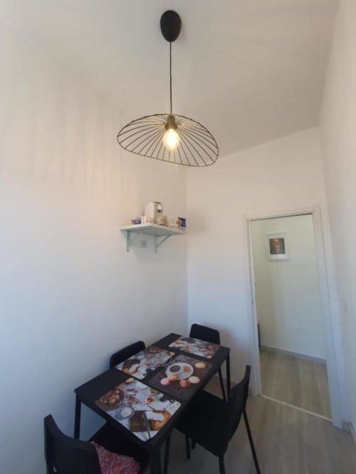 Zona pranzo contemporanea nell'appartamento di Siracusa con tavolo nero, sedie e sospensione di design