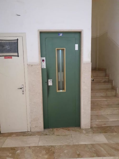 Porta ascensore verde con finestra in vetro nel corridoio della struttura Siracusa Sun&Home