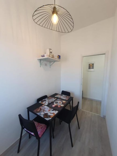 Moderna zona pranzo nell'appartamento di Siracusa con tavolo nero, sedie e lampada a sospensione