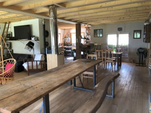 Séjour ouvert avec salle à manger et salon aux poutres apparentes, tables, télévision et vue montagne