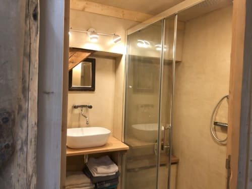 Salle de bain moderne avec vasque blanche, meuble bois et douche vitrée dans chalet de montagne aux Chalets de l'Eau