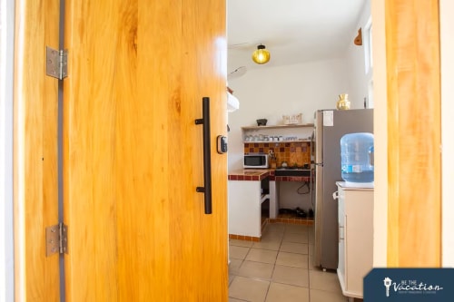 Entrance to Burbuja apartment at Anita Ocean View, Puerto Vallarta. Wooden doors open to kitchen with appliances and dining