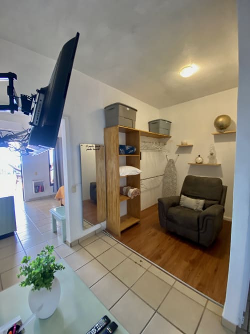 Cozy studio apartment at Anita Ocean View, Puerto Vallarta with wooden storage, dark armchair, and kitchenette