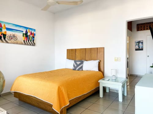 Bright bedroom in Anita Ocean View Puerto Vallarta with wooden bed, orange bedding, white nightstand, and colorful artwork on